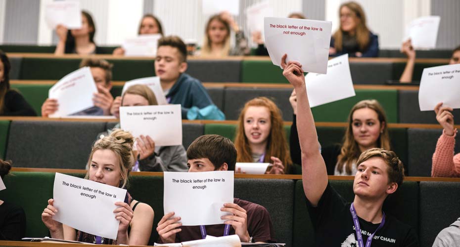 Group of students in lecture theatre holdig up signs.