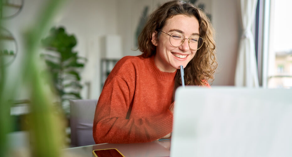 Smiling girl on computer with pen and phone